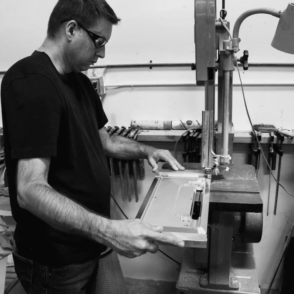 Engineer at industrial saw working on component for medical software compliance.