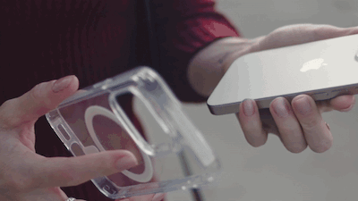 A person holds a clear phone case in one hand and a silver smartphone in the other,…
