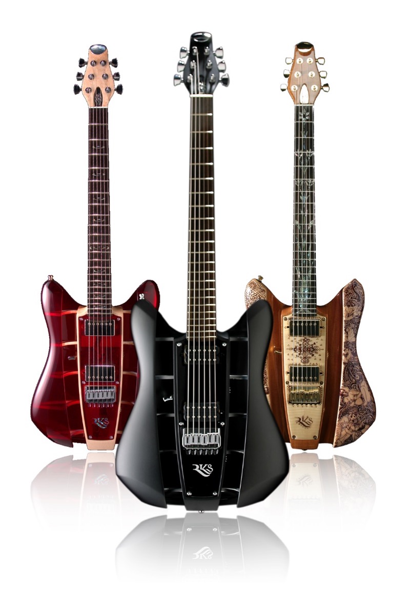 Three RKS electric guitars standing upright in red, black and carved natural wood finishes, each with an open slatted body