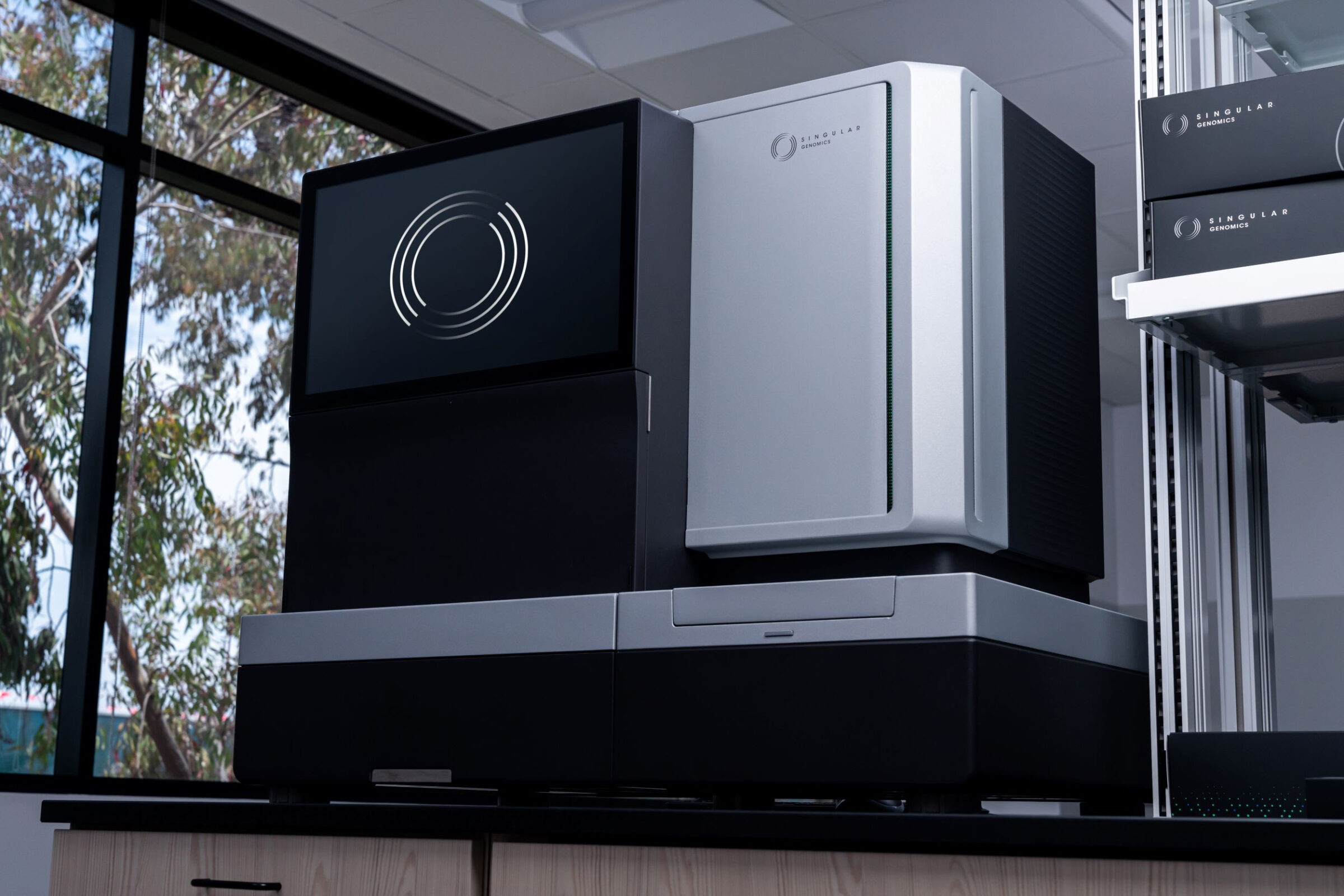 A large, modern genomic sequencing machine with a black and silver design sits on…
