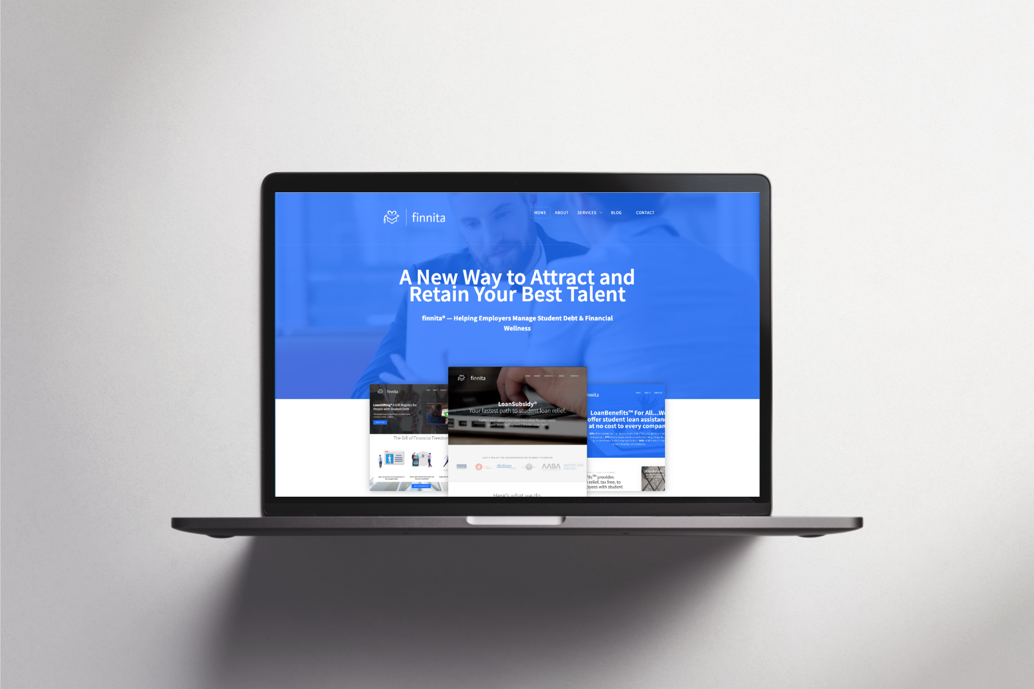 A laptop on a white surface displays a website with a blue and white design.