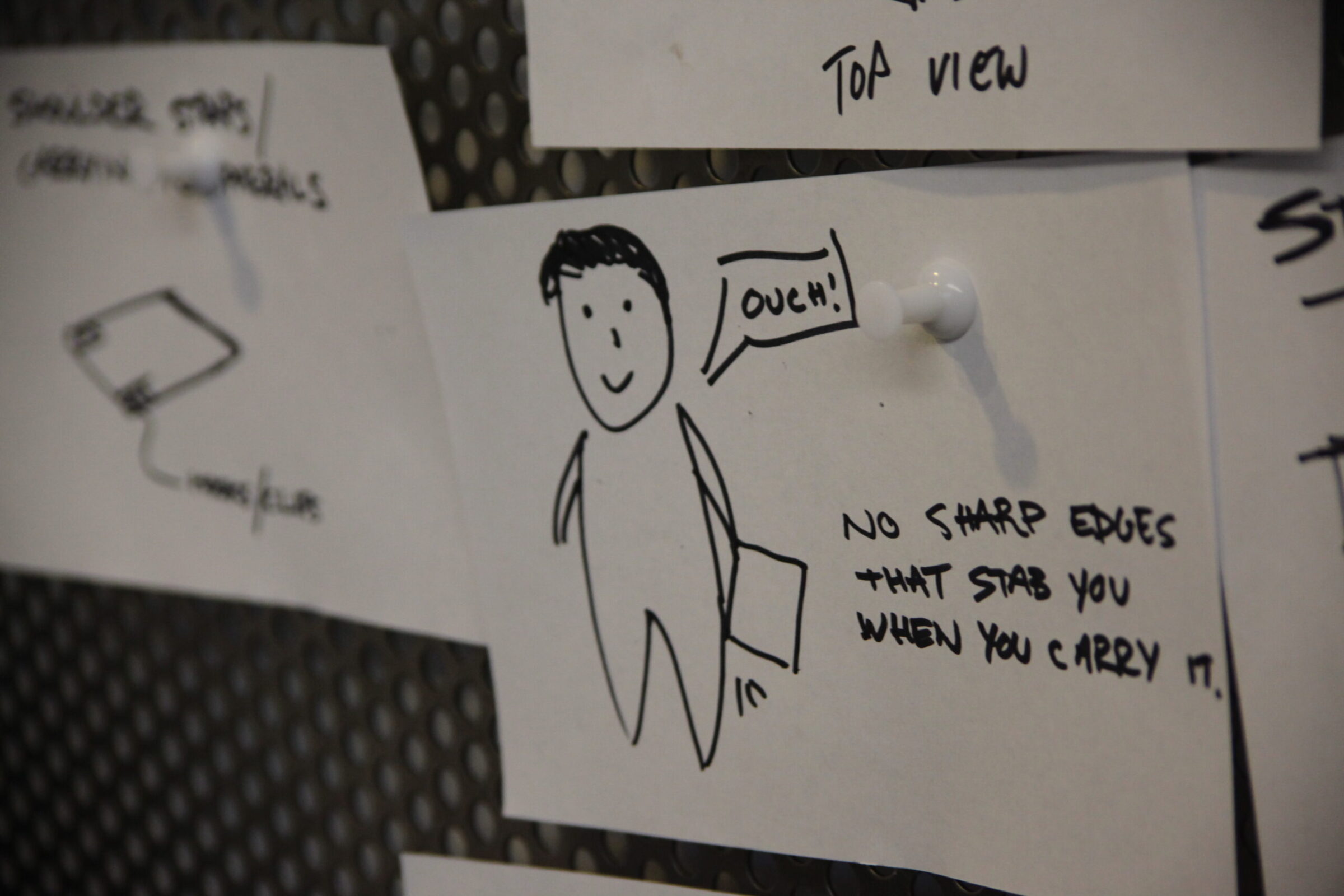 A hand-drawn sketch of a person holding a bag, saying Ouch! The note beside reads