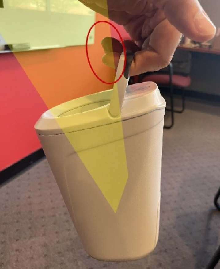A hand holds a white container by a handle, with colored shapes and a red circle…