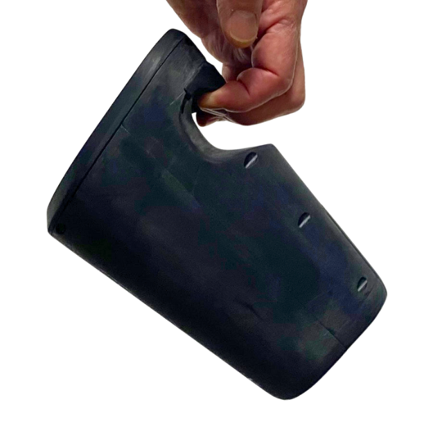 A hand holds a dark, cylindrical container with a built-in handle at the top, tilting…