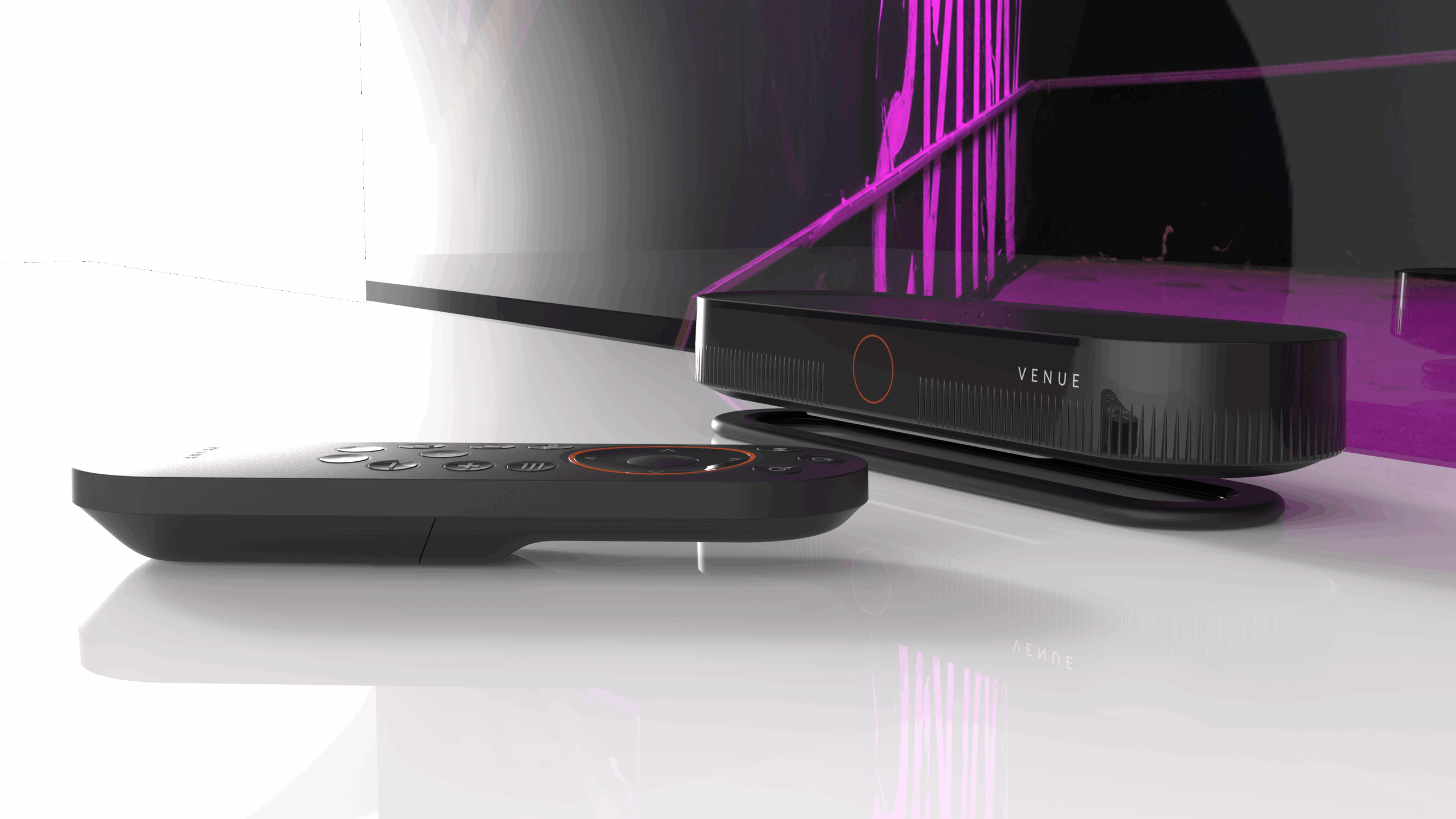 A black TV remote lies on a glossy white surface in front of a sleek Xcinex VENUE