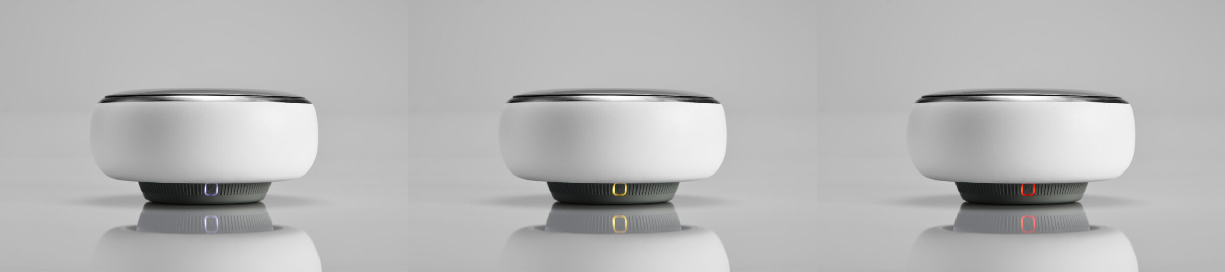 Three identical round, white smart speakers with dark tops are shown side by side.
