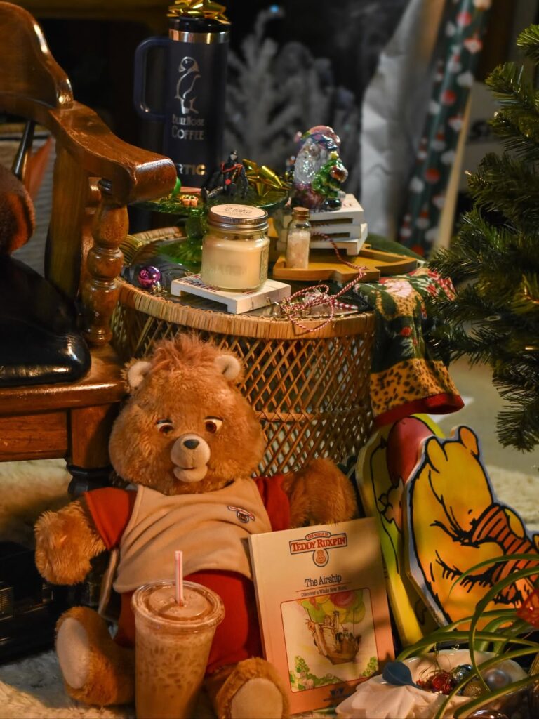 A cozy scene featuring a Teddy Ruxpin stuffed bear, an iced coffee, The Arnold Lobel…