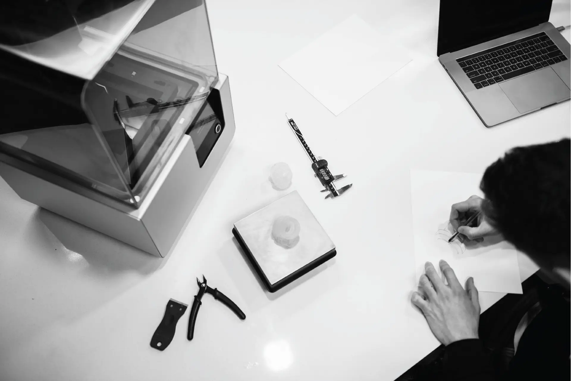 3D printer and calipers arranged with prototype components on a workstation