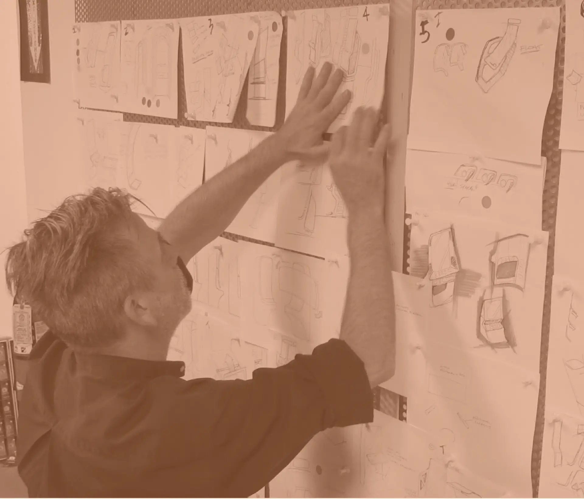 RKS Designer Putting sketches of the IGT Poker Bartop up on a wall at RKS Design