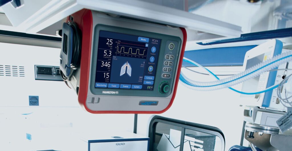 A medical monitor displays vital signs, including heart rate, oxygen level, and lung function, in a hospital setting. The screen shows numerical readings, waveforms, and graphical data.