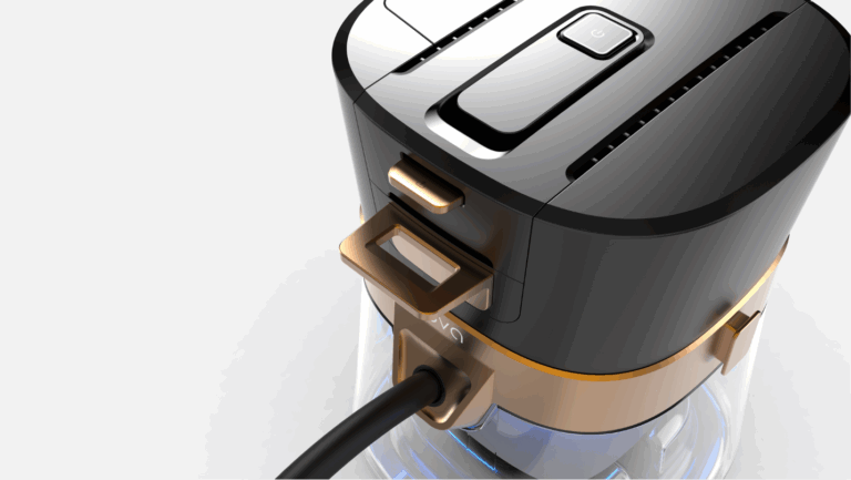 Close-up of a modern black and gold electronic device with a power button and a cable connected to its side, featuring sleek, curved edges and a transparent lower section.