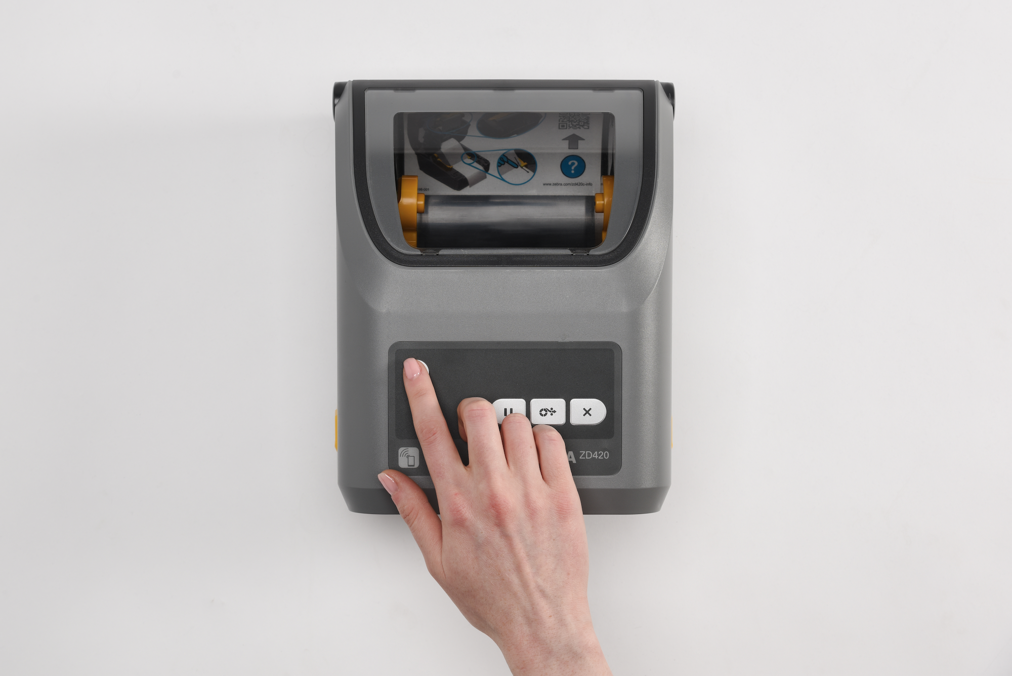 Hand pressing a button on top of the Zebra ZD420 printer, with cartridge visible inside the clear lid