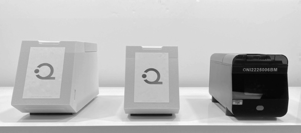 Three rectangular devices are displayed side by side on a white surface, reflecting the clean design often seen in the Life Science Market. The two on the left are white with a minimalist logo; the black device on the right is labeled ONJ2225006BM.