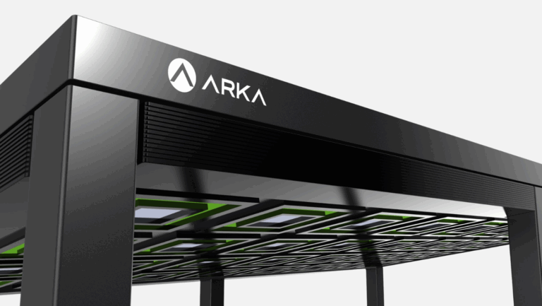 Close-up of a modern black kiosk or charging station with the ARKA logo on the top panel and a grid pattern underneath. The design features sleek lines and a minimalist aesthetic.
