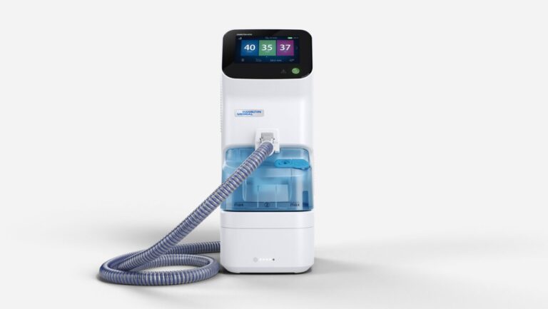 A Hamilton-HF90 medical device with a digital screen displaying numbers, a blue water chamber, and a flexible hose attached. The white unit stands upright on a plain, light background.
